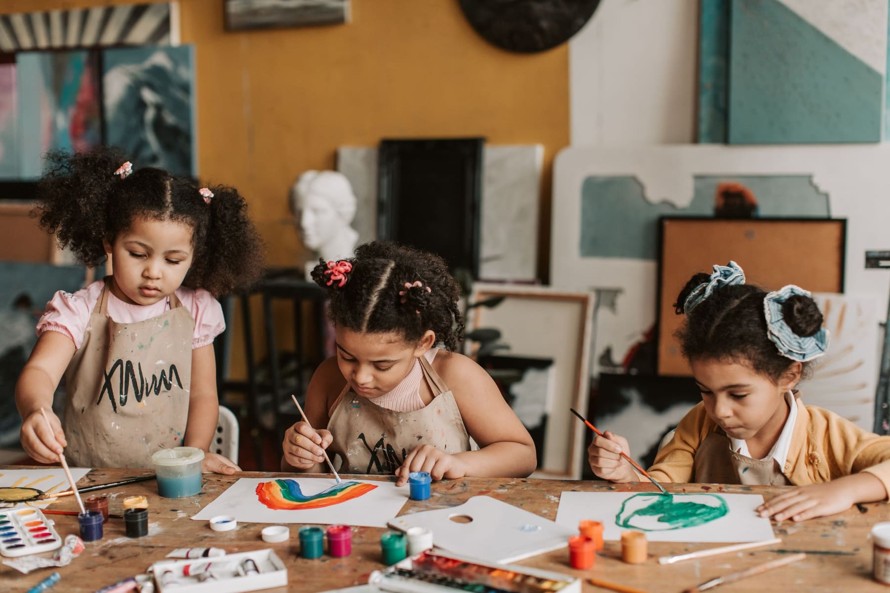 Young children painting together at a wooden table
