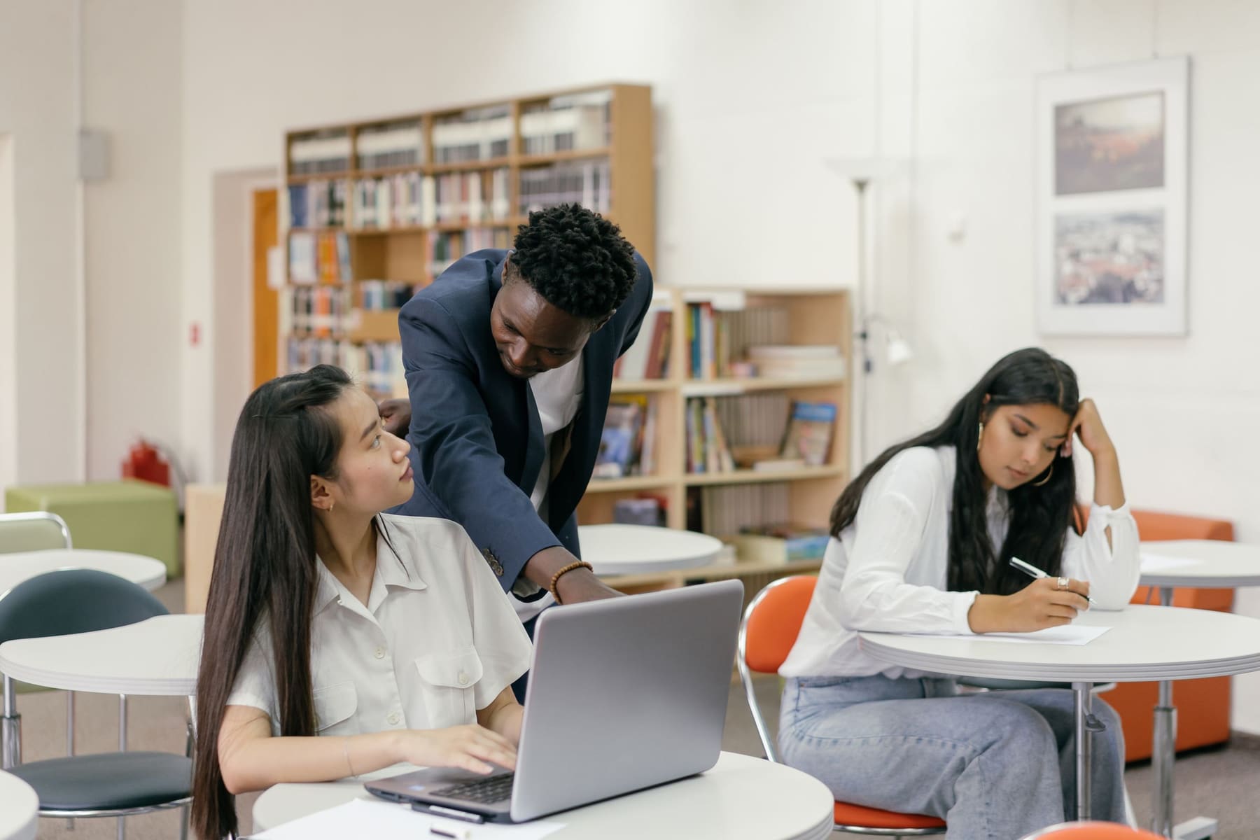 A teacher helping students with work on their laptops